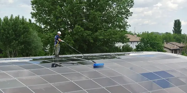 Ein Arbeiter reinigt Solaranlagen auf einem Dach zur optimalen Photovoltaik-Leistung.