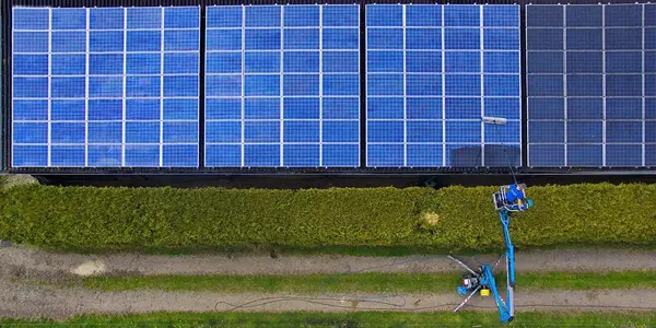 Solaranlage auf Hausdach wird mit Hubarbeitsbühne gewartet, erneuerbare Energie.