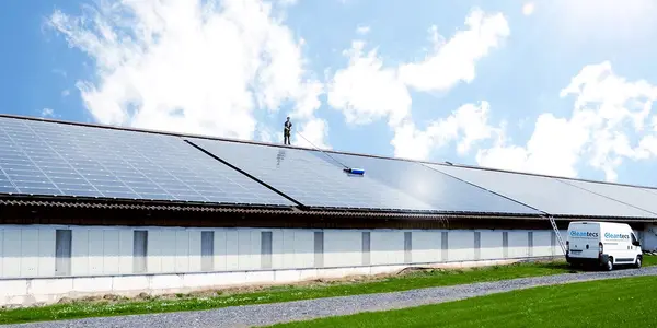 Ein Mitarbeiter reinigt große Photovoltaikanlage auf Hallendach für Solarreinigung.